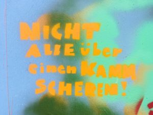 Aufgesprühter Spruch und buntem HIntergrund: Nicht alle über einen Kamm scheren.