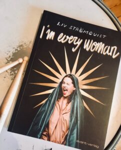 Foto vom Buch "i'am every woman" auf einer Trommel mit Drumsticks daneben liegend.