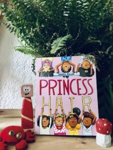 Foto vom Kinderbuch: Princess hair. vor einer grünen Pflanze, mit kleinem roten Holzfigürchen