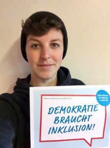 Amélie Sarramagnan mit Schild: Demokratie braucht Inklusion