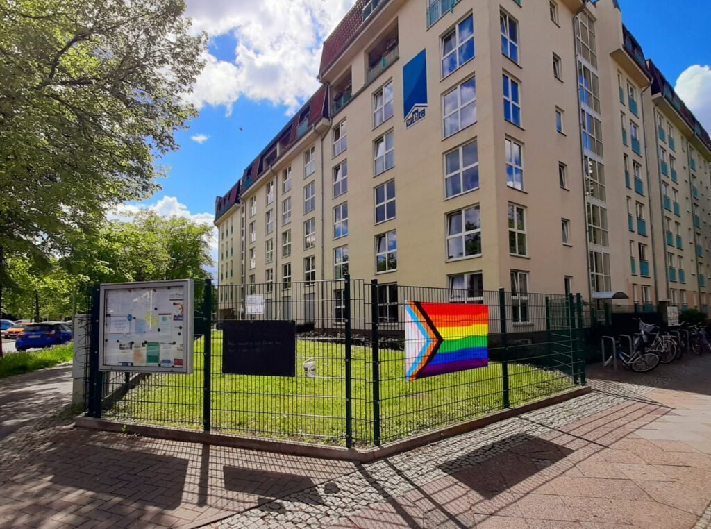 Zaun mit Fragetafel und Regenbogenflagge