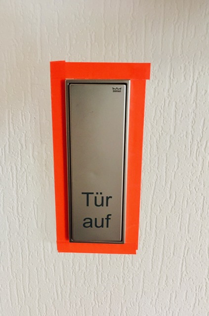 Foto des automatischen Türöffners mit buntem Klebeband umrahmt