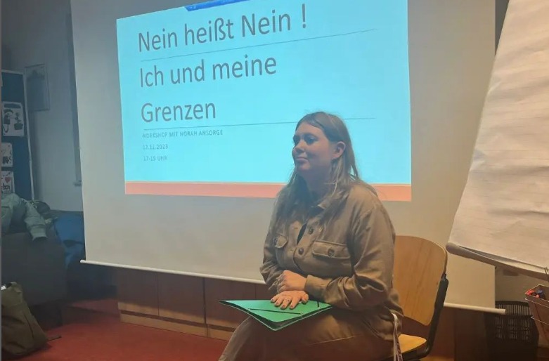 Auf dem Bild zu sehen ist eine junge Frau. Im Hintergrund ist eine angebeamte PowerPoint Seite zu sehen. Auf dieser steht: Nein heißt Nein! Ich und meine Grenzen!